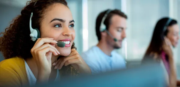 Mulher sorrindo com um headset conversando com o cliente na sala de atendimento